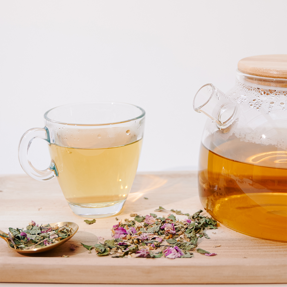 Tasse remplie d'une infusion de plantes médicinales pour les règles douloureuses.  L'infusion est sur un plateau avec une théière, pour un rituel bien-être du cycle menstruel.  