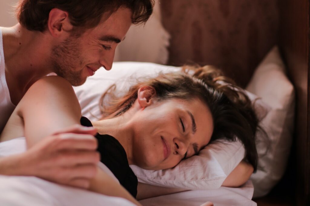 Un couple intime et complice allongés dans un lit. Ils ont fait l'amour, car cela soulage les règles douloureuses. 