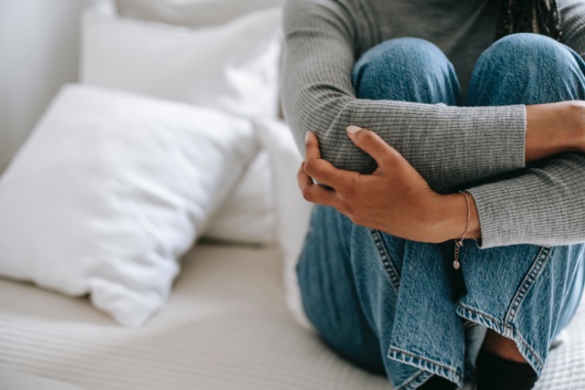 On voit une femme recroquevillée sur son lit, les bras croisés. Elle a honte car elle a ses règles et elle crains d'en parler car les règles sont taboues