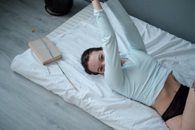 Jeune femme allongée sur son matelas.  Elle est en phase prémenstruelle de son cycle menstruel féminin. Elle prend du temps pour elle, se repose, semble détendue et sereine;  